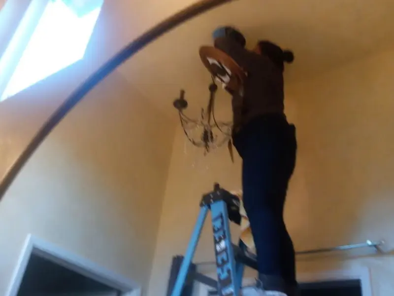 Electrician installing a chandelier in a Washington Terrace residence